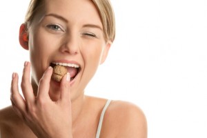 A woman biting a uncracked nut to demonstrate cracked teeth services