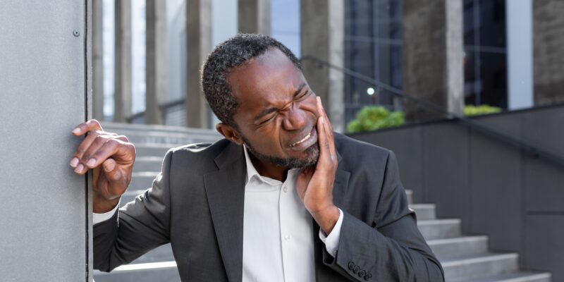 man in an office park suffering from severe tooth pain, possible need for endodontics