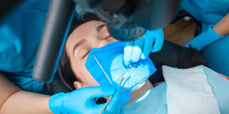 endodontic treatment of dental canals in the lower molar permanent tooth molar with endodontic file with apex locator, tooth with clamp attached to it by cofferdam