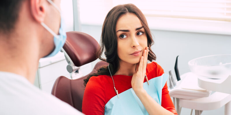 young woman sitting in a dental office in tooth pain