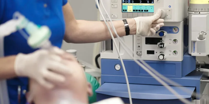 An anesthesiologist monitors the condition of a patient under dental sedation