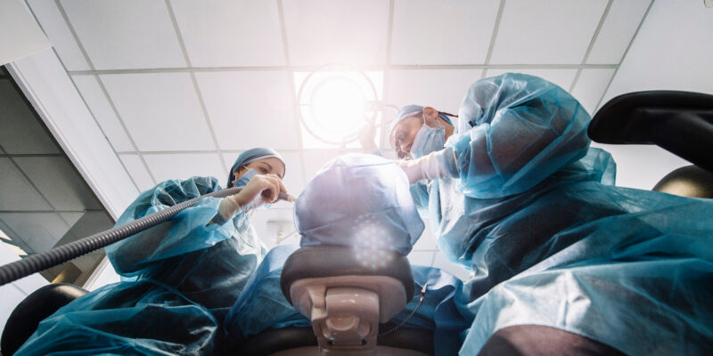 dentists over a patient during oral surgery