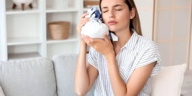 young woman sitting on couch with ice on her jaw, tooth ache