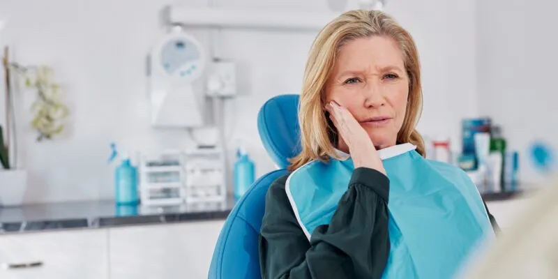 Beautiful adult woman holding her cheek showing signs of dental discomfort, toothache